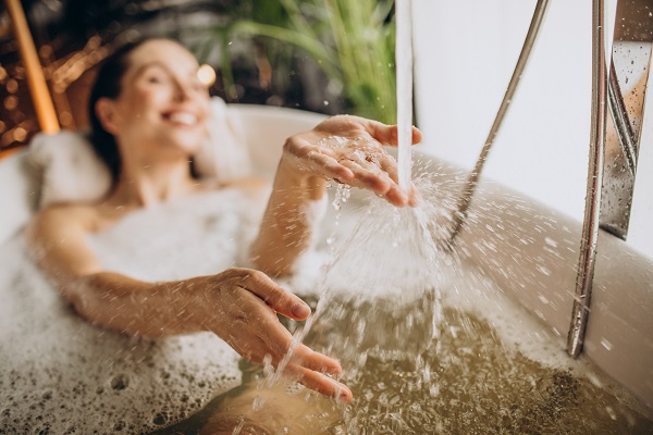 Acqua calda senza sprechi Donna si rilassa con un bagno caldo.