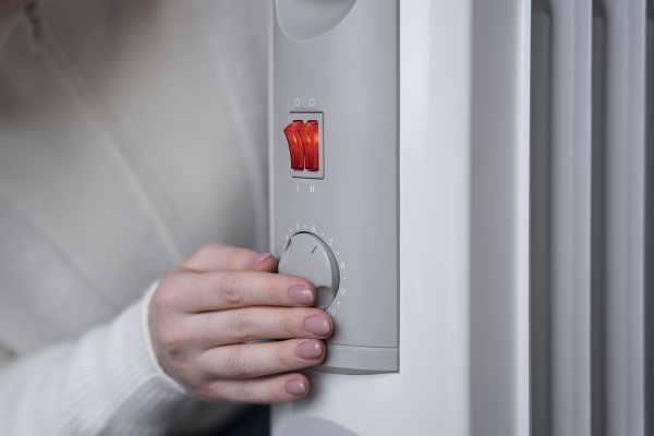 Scegliere nuovi impianti riscaldamento Donna accende l'impianto di riscaldamento di casa.